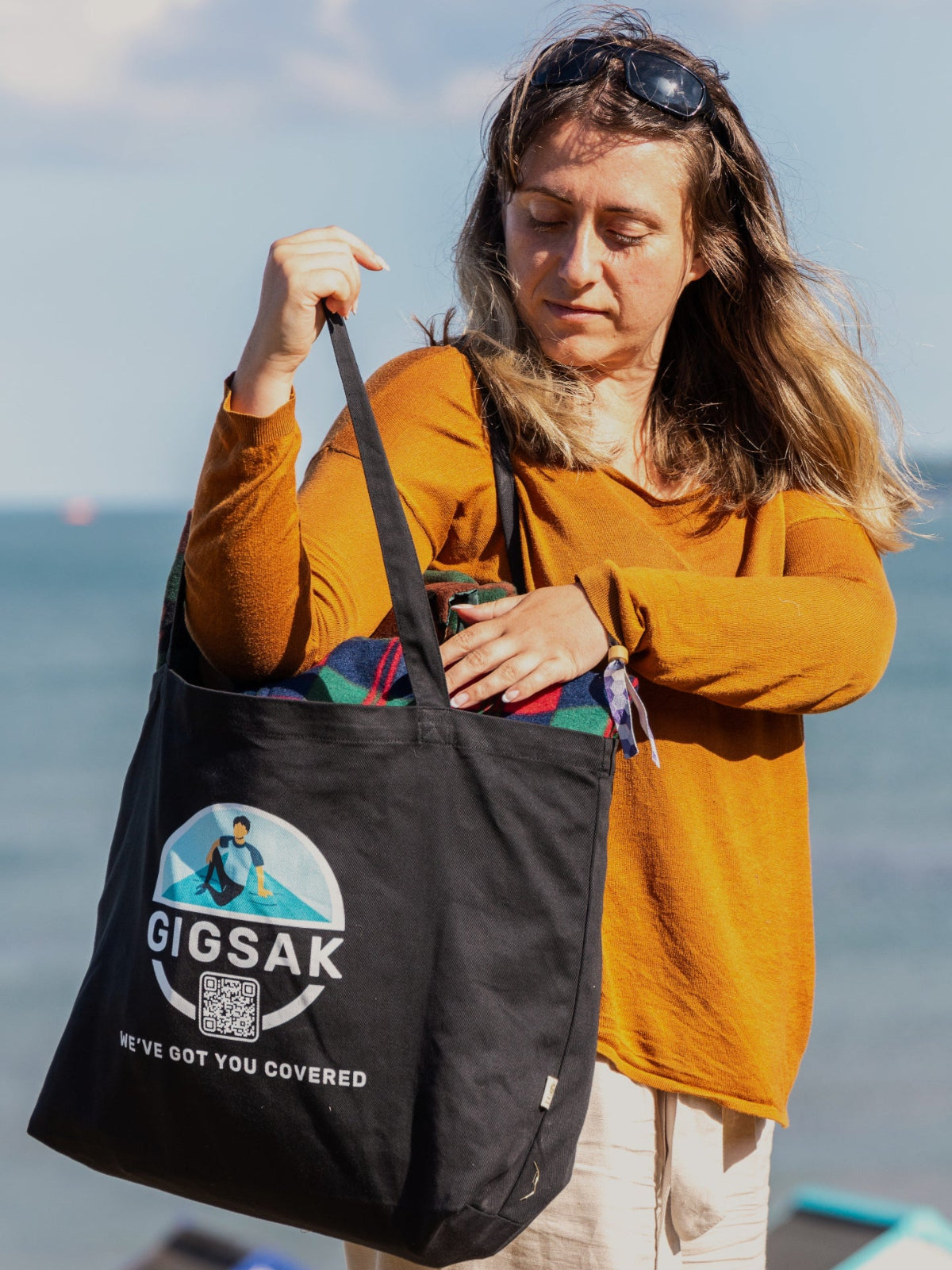 Woman checking her black GIGSAK tote bag, two GIGSAK inside the tote bag, the tote hanging from her shoulder.