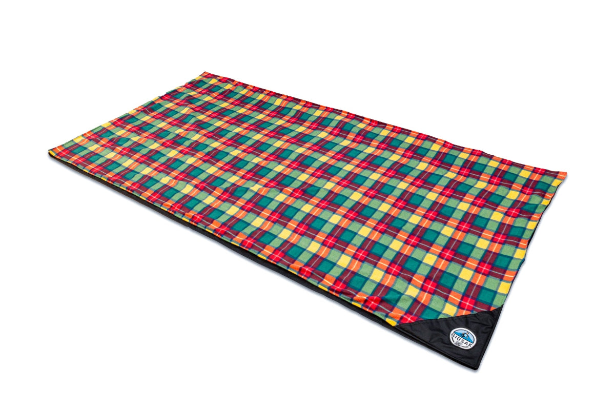 A GIGSAK Giant outdoor waterproof blanket is the only outdoor waterproof blanket you can sit inside. It features a sleek red, orange, yellow, and green tartan with a black waterproof design. GIGSAK features a unique, hidden, cosy shelter to protect against the wind and rain. Simply turn GIGSAK inside out to stay warm and dry. GIGSAK is perfect for family picnics, BBQs, the beach, festivals, open-air cinema, fireworks, camping, and more.